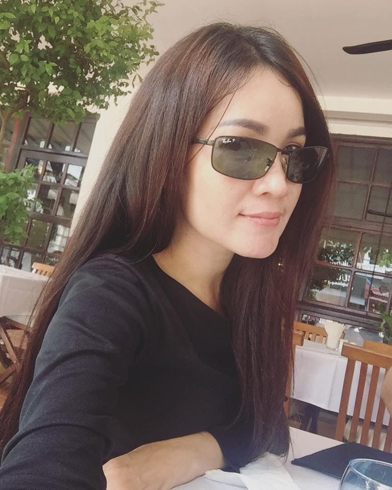 Woman with long brown hair wearing sunglasses and a black shirt at a restaurant table.